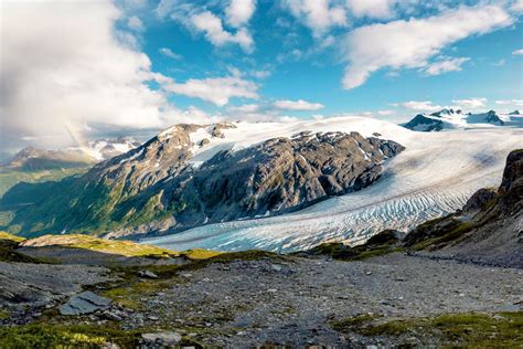 Helicopter carefully landing on a vast, crevasse-filled Alaskan glacier during a tour