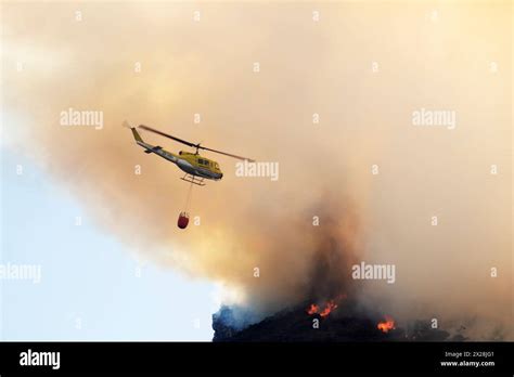 helicopter dropping water over scorched hills in Canary Islands wildfire zone