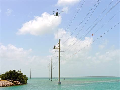 helicopter lineman replacing insulator while suspended above remote terrain