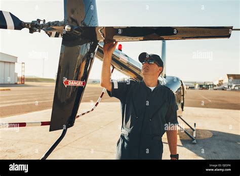 Helicopter pilot performing pre-flight inspection on a runway