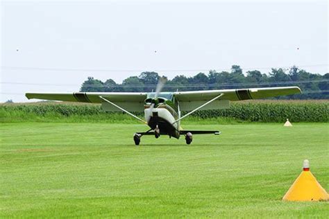 high-wing Cessna rolling gently across a soft, uneven grass field during rollout phase