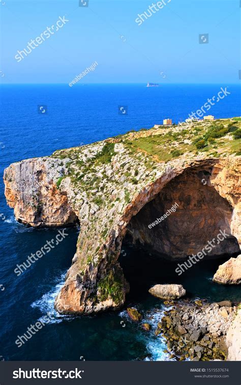 hiker overlooking Malta’s cliffs with sea caves below