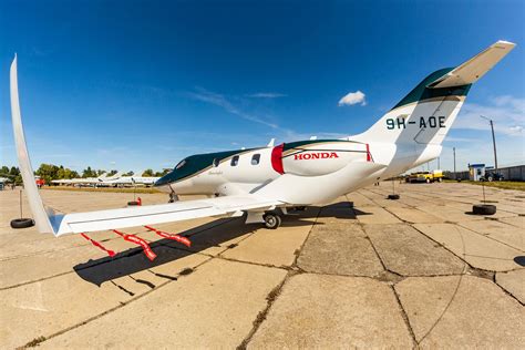 HondaJet parked in private hangar with luxury SUV beside it