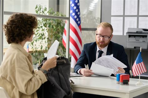 Immigrant worker consulting with immigration attorney in office with legal documents and laptop open