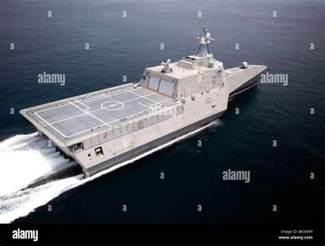 Independence-class LCS underway with helicopter hovering near the flight deck