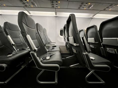 interior of Frontier Airlines A320 showing narrow seating and tray tables folded