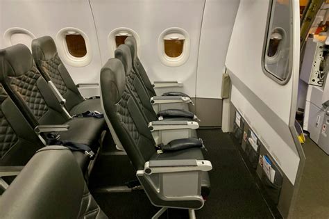 Interior view of Frontier Airlines cabin with slimline seating and tray tables folded