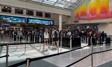 International airport security line with signs referencing razor policy and personal items