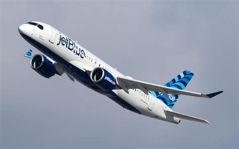 JetBlue Airbus A220 taking off with Caribbean coastline in background