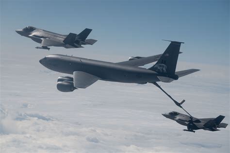 KC-135 Stratotanker performing aerial refueling with fighter jet mid-air