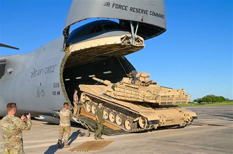 Lockheed C-5 Galaxy with rear cargo ramp open, loading armored vehicles
