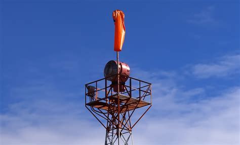 maintenance crew inspecting airport beacon atop an orange and white tower