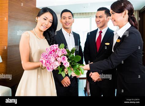 multicultural hospitality staff greeting international guests at hotel check-in counter