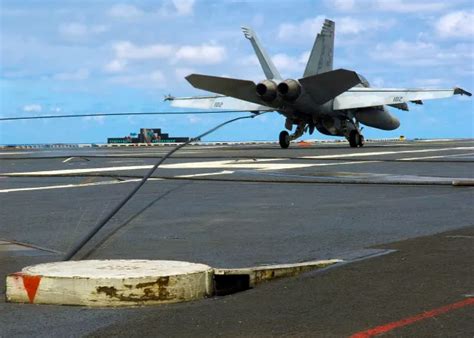 navy fighter jet catching arresting wire on aircraft carrier