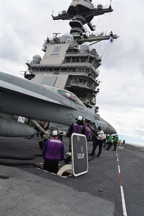Navy maintenance crew preparing Super Hornet for sortie on carrier deck