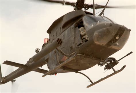 OH-58 Kiowa hovering over forest terrain during recon mission