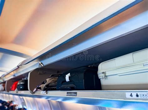 Overhead bins filled with carry-on luggage inside aircraft cabin