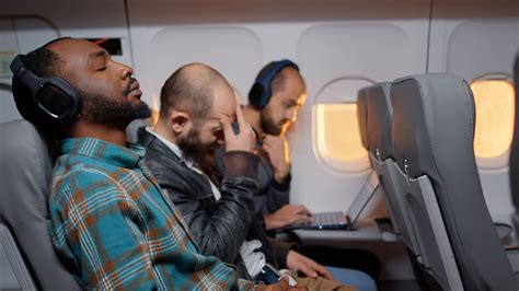 passenger sleeping across empty row on a red eye flight in economy class