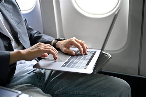 passenger using laptop connected to inflight wifi inside modern aircraft cabin