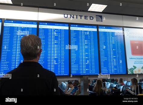 passengers at Newark Airport checking departure screens after United Dubai cancellation