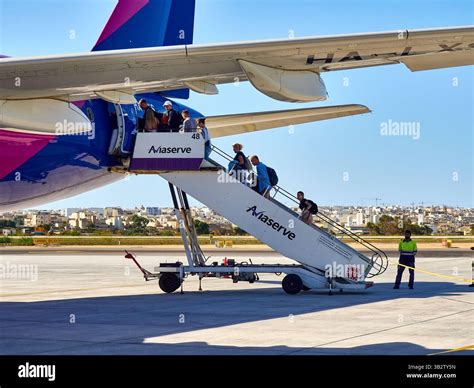 Passengers boarding an Air Malta plane via stairs at MLA in sunny weather