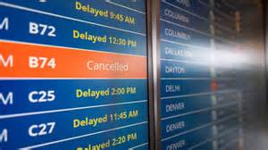 passengers checking flight status during widespread airline delays in US airport terminal