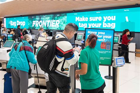 passengers checking luggage at a Frontier Airlines baggage counter