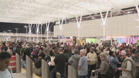 passengers waiting in long rebooking lines at houston airport during summer storm disruptions