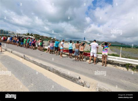 people clinging to fence during jet blast at Maho Beach