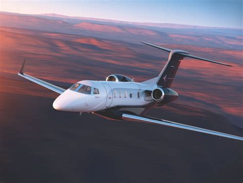 Phenom 300E flying above city skyline during sunset with wingtip view