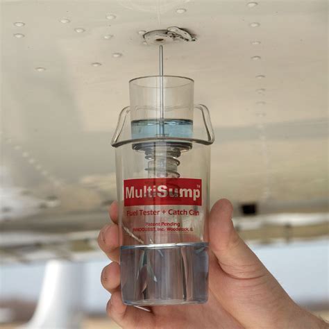 pilot inspecting fuel sample for water and debris from fuel strainer sump