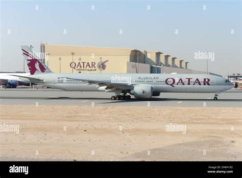 qatar airways boeing 777 with qsuite livery taxiing on runway at doha airport