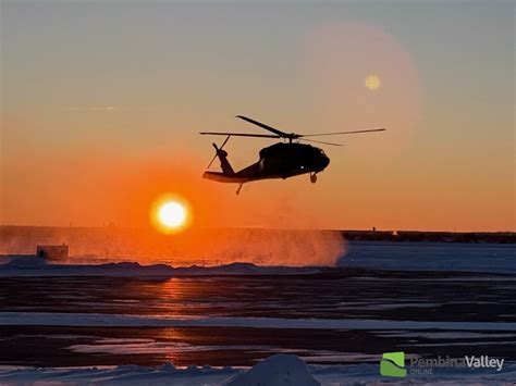 RCMP helicopter performing nighttime landing in designated secure zone near Nakiska Ski Hill