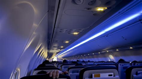 red-eye flight cabin interior with dimmed lights and sleeping passengers