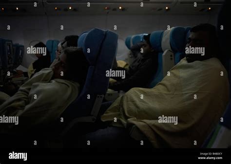 red eye flight cabin with dimmed lights and passengers sleeping in economy seats