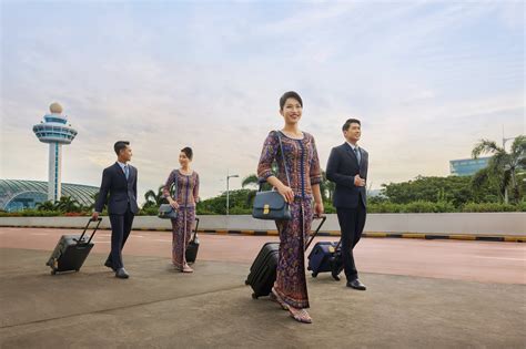 Singapore Airlines cabin crew walking through terminal amid passenger crowd