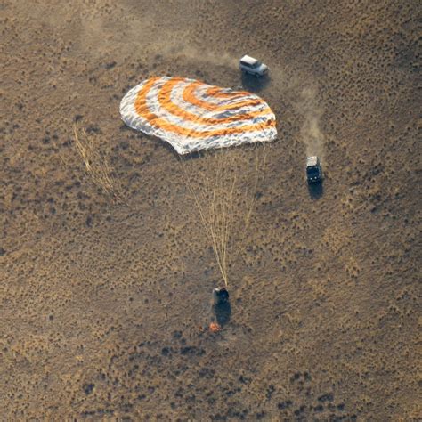 Soyuz spacecraft landing on Kazakhstan steppe with recovery teams