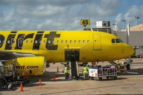 Spirit aircraft on tarmac with baggage carts loading multiple bags