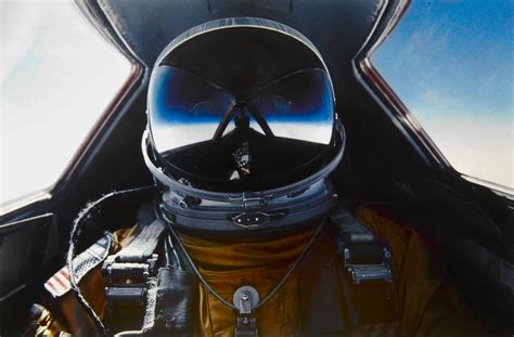 SR-71 pilot suit holding food tube near cockpit window interior