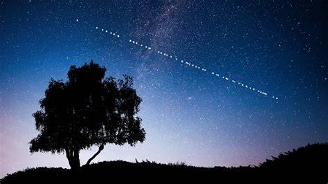 Starlink satellite train appearing as a line of bright lights across a clear night sky