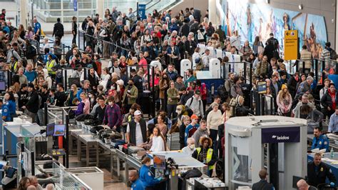 stranded tourists checking flight cancellations on mobile devices at Denpasar airport