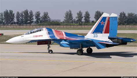 Su-30SM in Russian colors banking mid-flight above forested terrain
