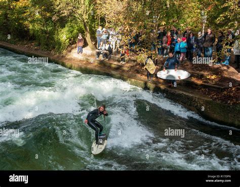 surfers on eisbach river wave in english garden munich 2025