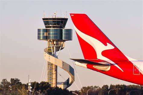 Sydney Kingsford Smith Airport control tower overseeing Qantas aircraft on taxiways