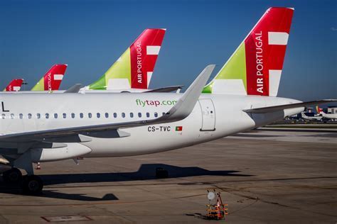 tap air portugal aircraft departing lisbon with city rooftops and tagus river below
