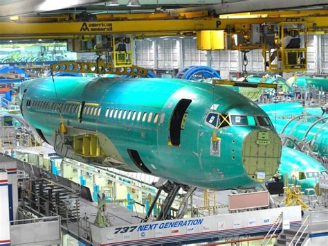 Technicians inspecting a 737 MAX fuselage inside Spirit AeroSystems composite fabrication bay