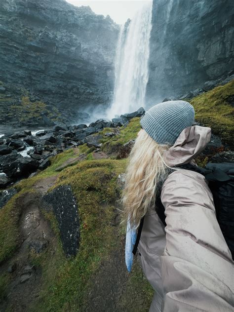 Tourists admiring a dramatic waterfall in the Faroe Islands
