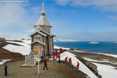 tourists in expedition parkas walking near penguin colony at King George Island