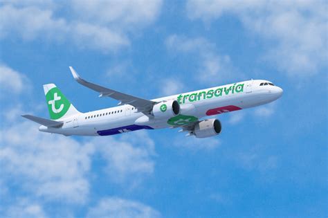 Transavia aircraft mid-flight over European coastline with sunset in background