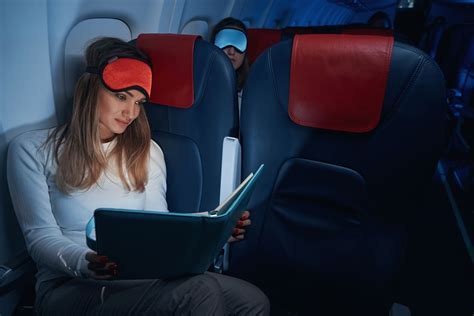 traveler wearing neck pillow and eye mask on a red eye flight